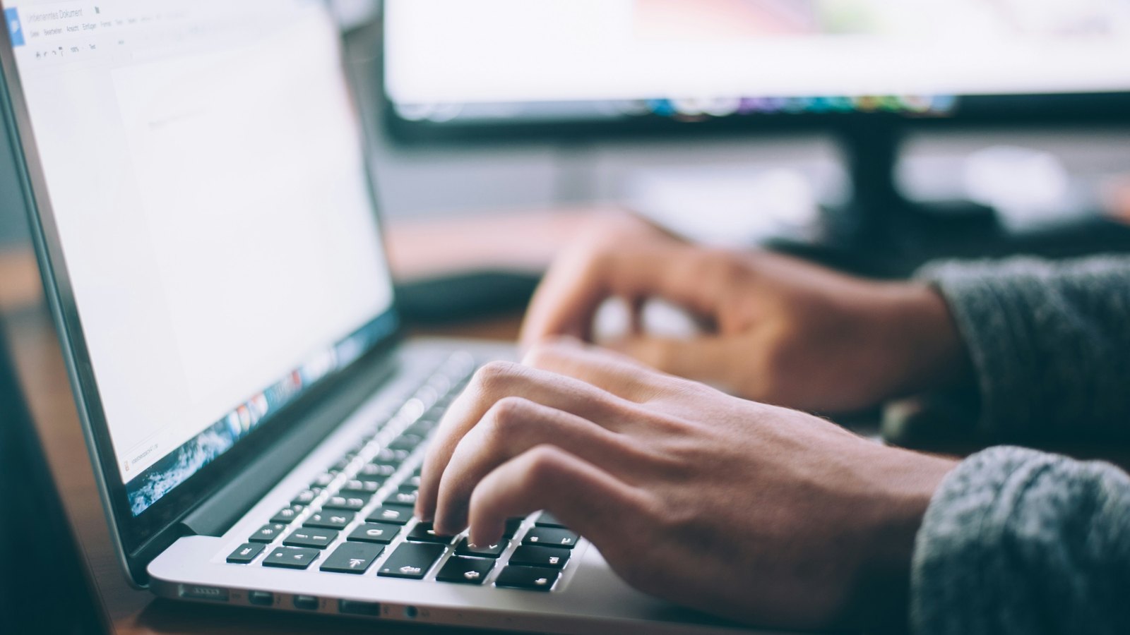 Hands typing on a laptop in an office workspace