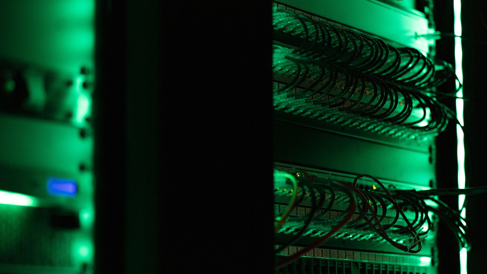 Server rack with cables and green status lights in a data center